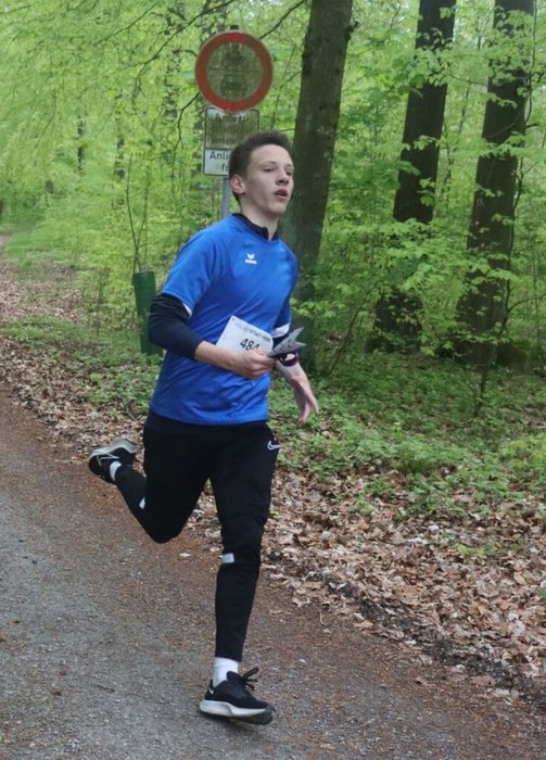 Ein teilnehmender Schüler läuft durch den Wald auf einem befestigten Weg