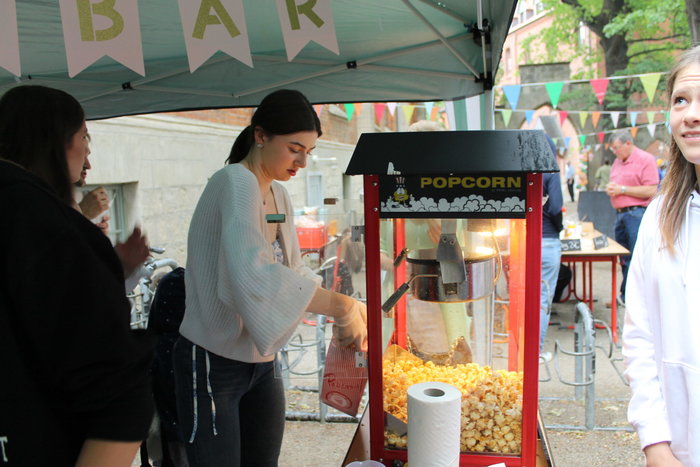 Eine dunkelhaarige Schülerin füllt Popcorn aus der Maschine in eine Tüte