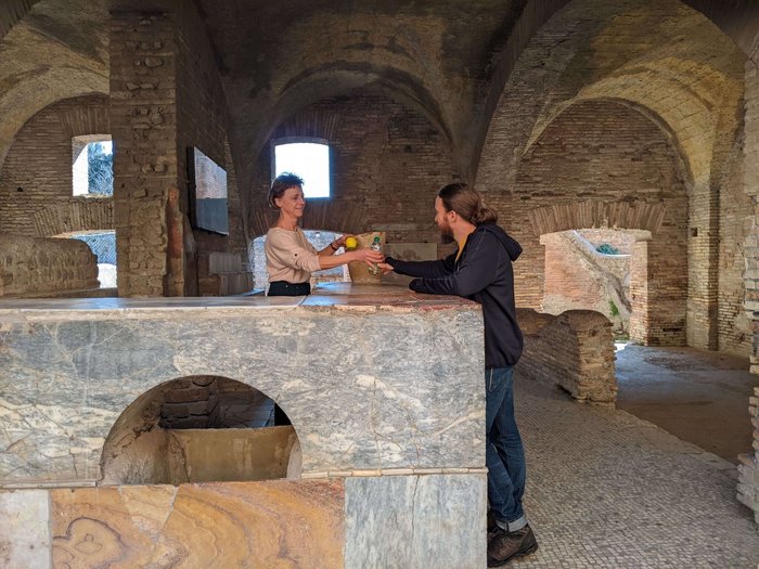 Ein Frau reicht einem Mann eine Wasserflasche und einen Apfel