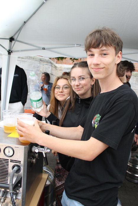 Zwei Schülerinnen und ein Schüler servieren Getränke