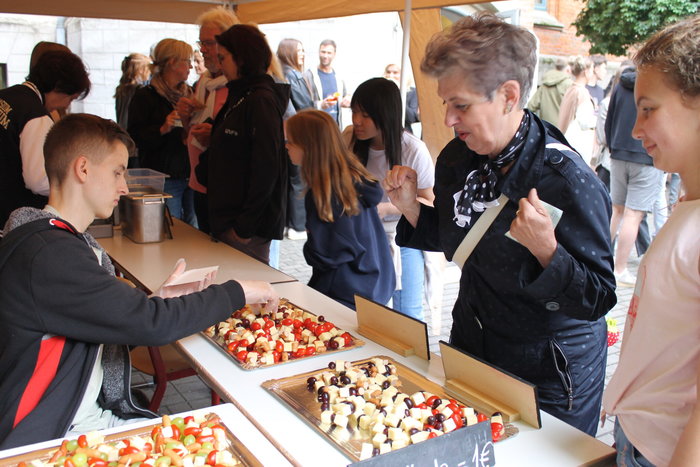 Ein Schüler verkauft Essenspieße an eine Frau