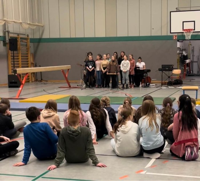 Schülerinnen und Schüler sind in der Turnhalle versammelt