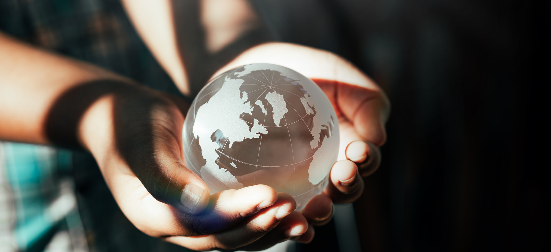 Eine PErson hält eine Weltkugel aus Glas in ihren Händen.