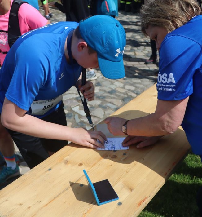 Eine Frau stempelt einen Pass eines Schülers, der an dem Lauf teilnimmt