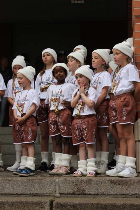 Junge Schülerinnen und Schüler mit weißen Mützen und T-Shirts und Lederhosen