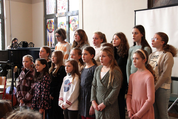 Mädchenchor singt und wird von einer Frau am Flügel begleitet